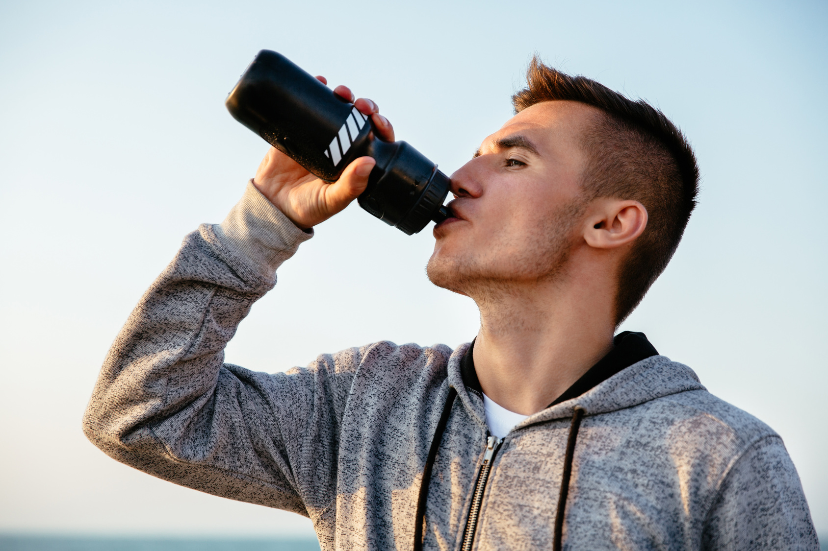 Пил бутылку. Спортсмен пьет воду из бутылки. Спортсмен пьёт из бутылочки. Спортсмен пьющий из бутылки. Парень с фотоаппаратом пьет воду.